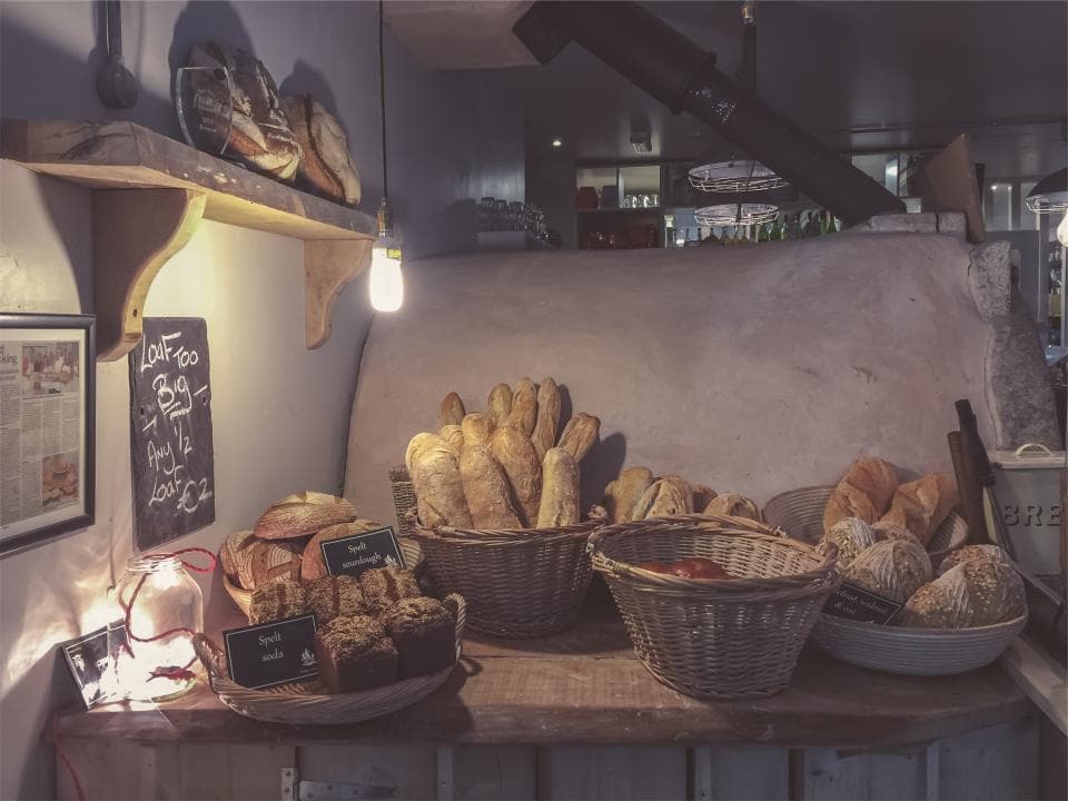 Baskets of bread and pastries on the shelves of a dimly lit bakery