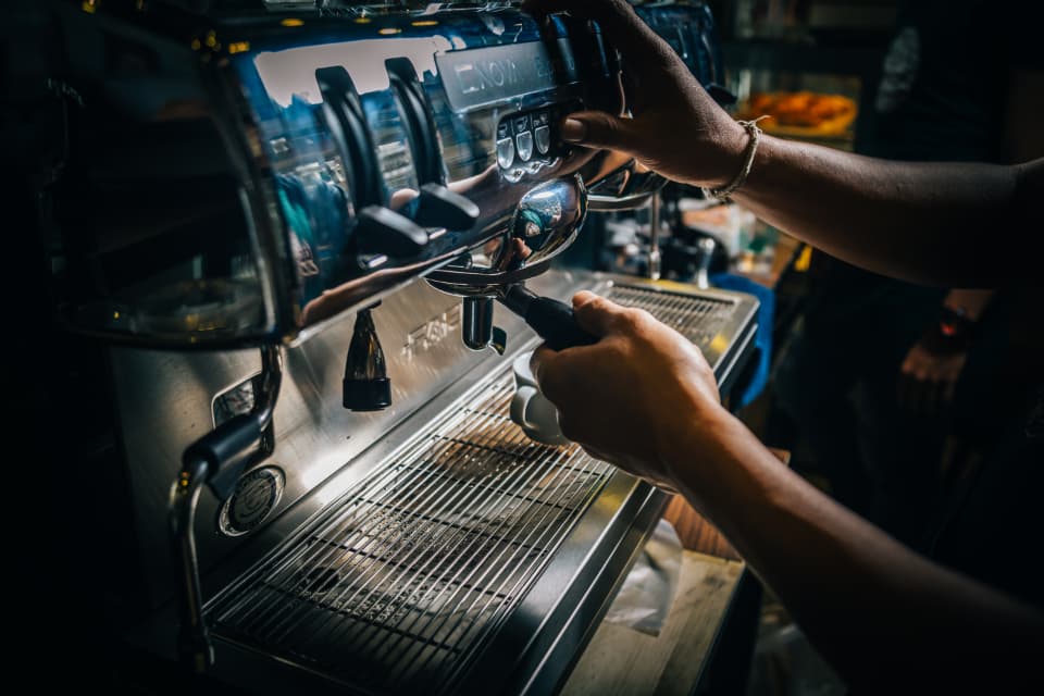 Hands working the group heads of an espresso machine